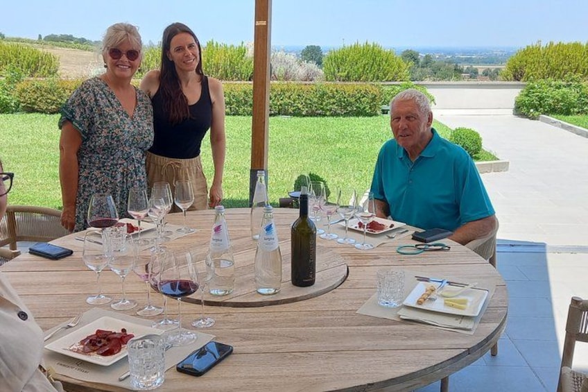 A round wooden table with wine glasses, bottles, and plates of food. 5