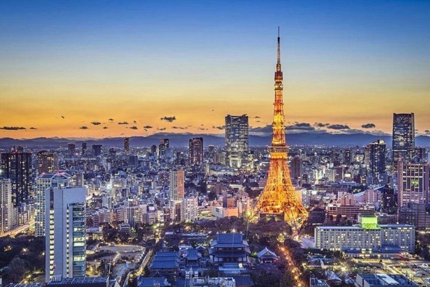 A cityscape with a prominent illuminated tower, likely the Eiffel Tower, surrounded by high-rise buildings and a clear sky. 1