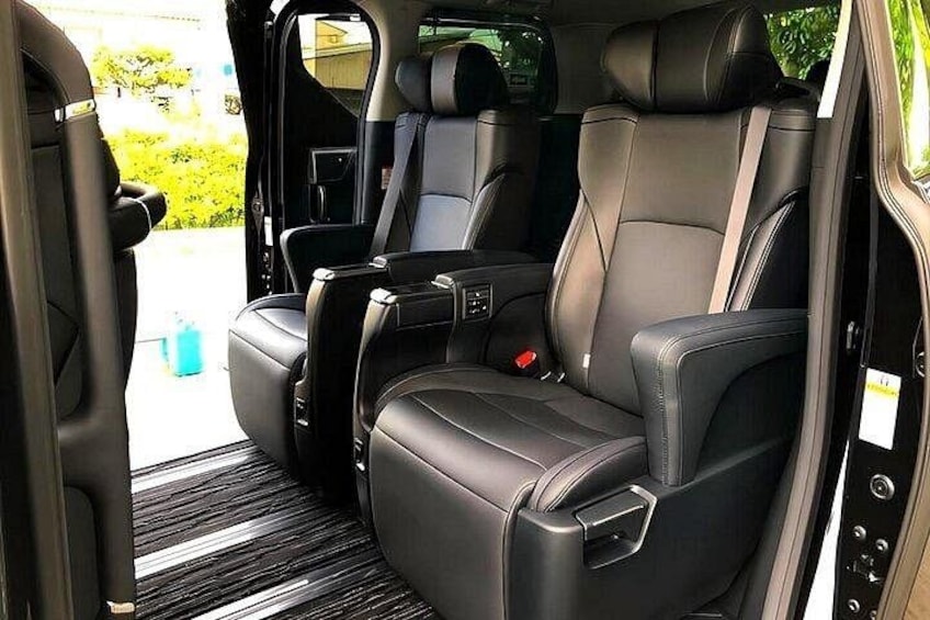 A vehicle interior with black leather seats, a center console, and a visible door handle. 4