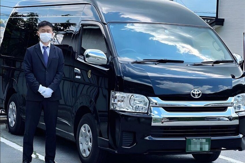A black Toyota van parked on a street with a person standing beside it. 3