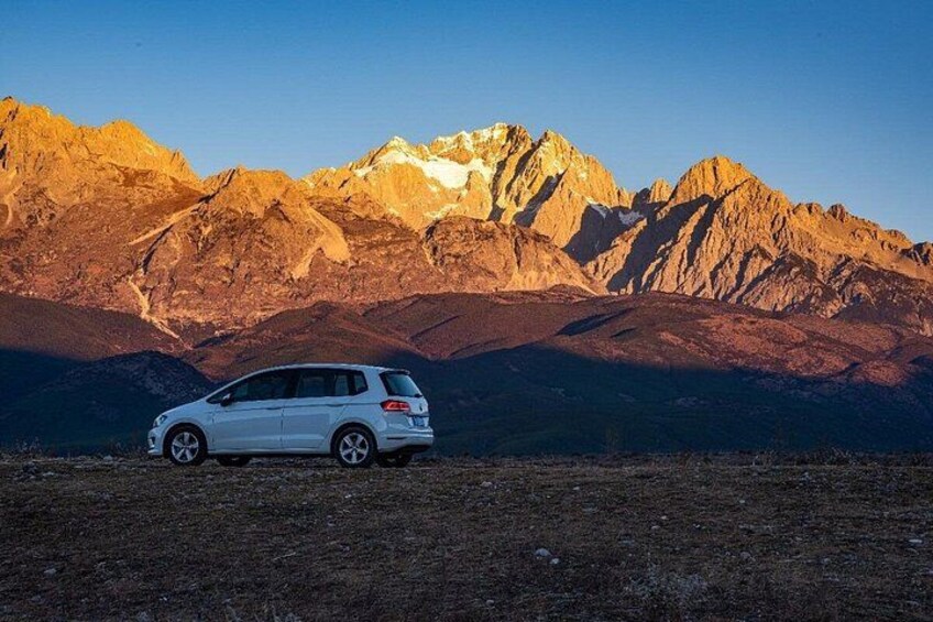 Un SUV blanco estacionado en un paisaje árido con una cadena montañosa al fondo. 3