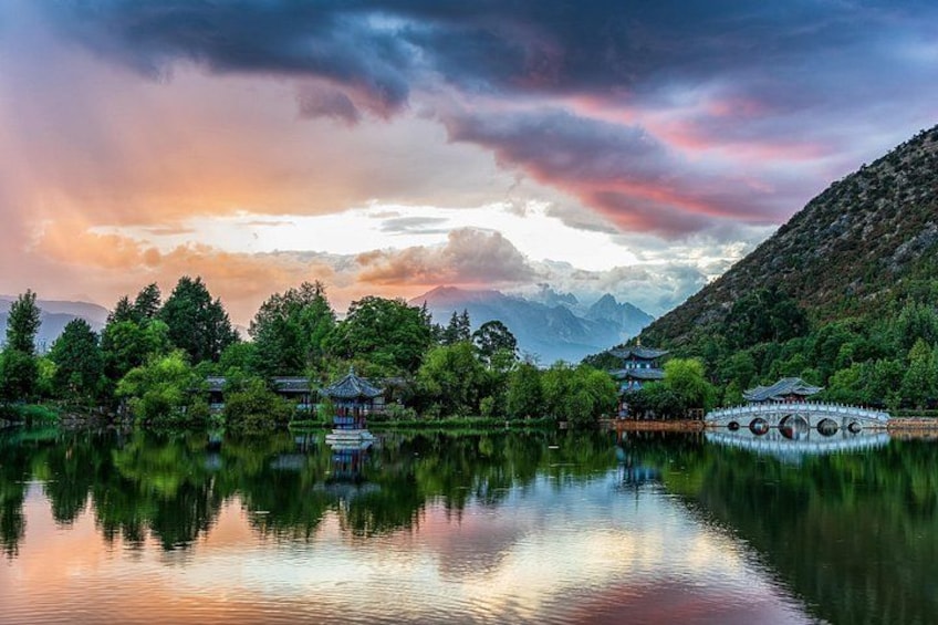 Un lago tranquilo con arquitectura tradicional, un puente y montañas al fondo. 5