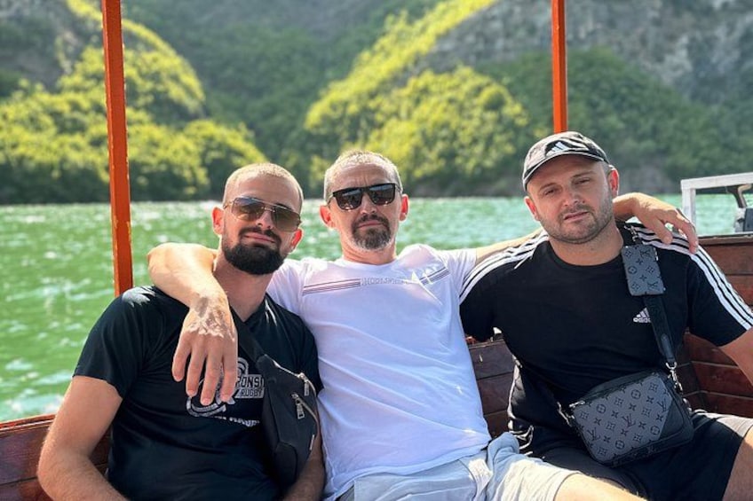 Three people on a boat with a mountainous landscape in the background. 2