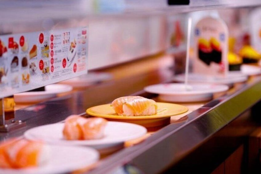 A sushi bar with various types of sushi displayed on plates. 2