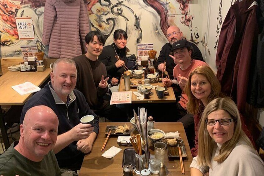 A group of people dining at a restaurant with traditional decor and a sign indicating free Wi-Fi. 1