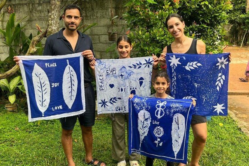 A family holding up fabric with leaf designs and text. 3