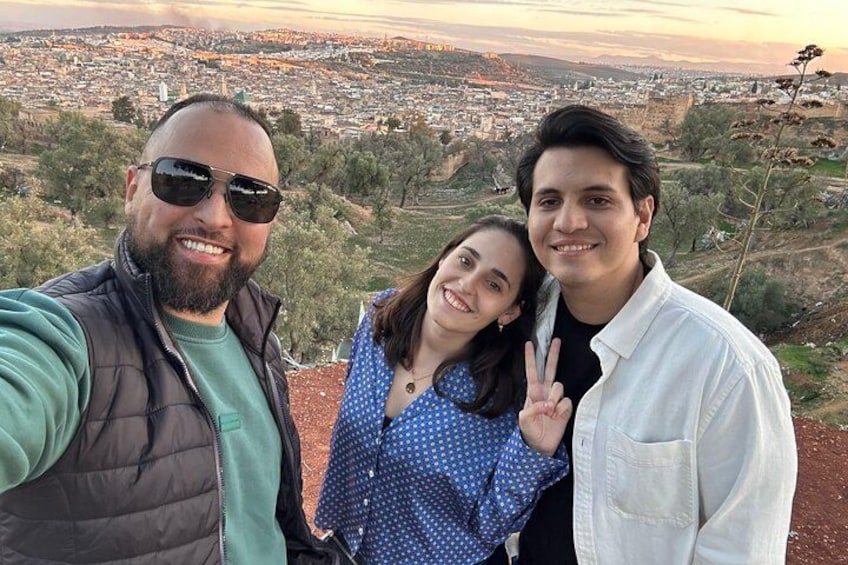 Tres personas tomándose un selfie con un paisaje urbano de fondo. 2