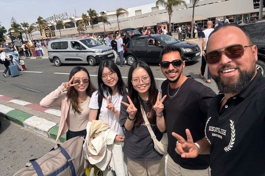 Un grupo de personas posando en una calle, con una furgoneta y coches al fondo. 3
