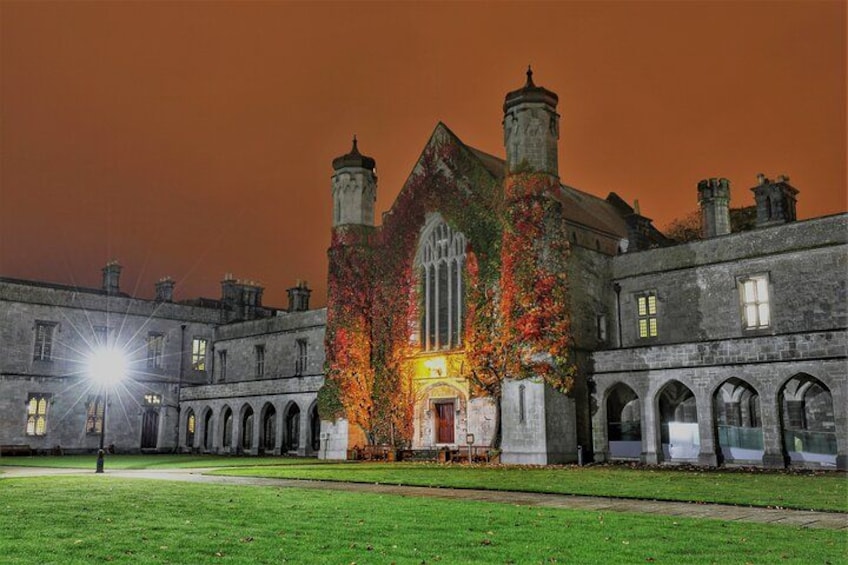 A historic building with ivy-covered walls and a large central window, surrounded by a courtyard with a well-maintained lawn. 2