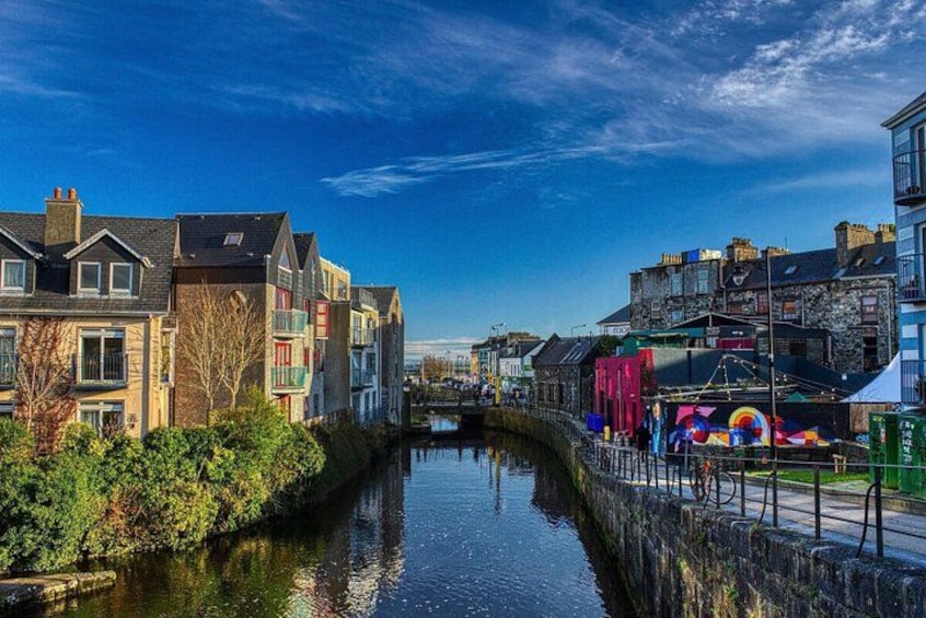 A canal with buildings on one side and a colorful mural on the other. 3
