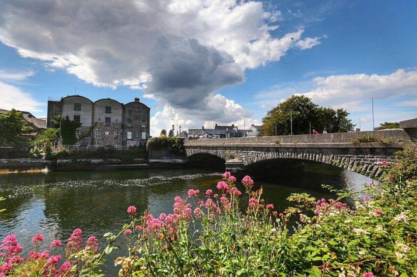 A stone bridge over a canal with buildings and flowers in the foreground. 3