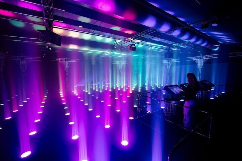 Una persona sta utilizzando una console da DJ in un locale notturno illuminato da luci LED colorate. 2