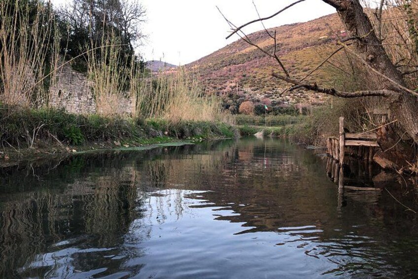 A calm river with a wooden bridge, surrounded by trees and hills. 2