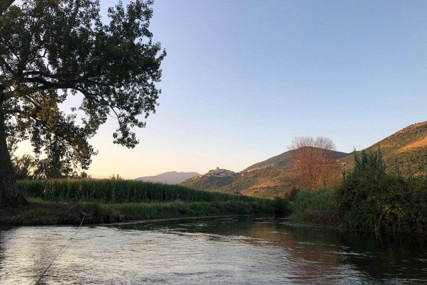 A river with a tree on the left, grassy banks, and hills in the background. 5