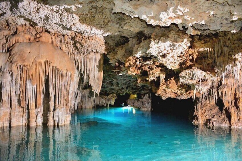 Une grotte ornée de stalactites et de stalagmites, une étendue d’eau et une personne dans un kayak. 5