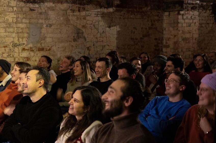 A group of people seated in an indoor setting with brick walls. 2