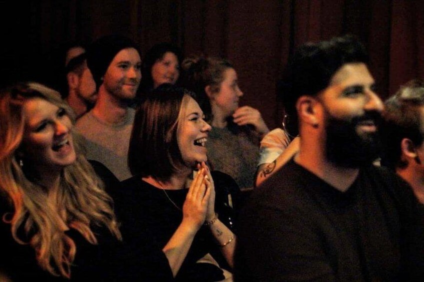 A group of people in a dimly lit indoor setting, likely a social event or gathering. 2