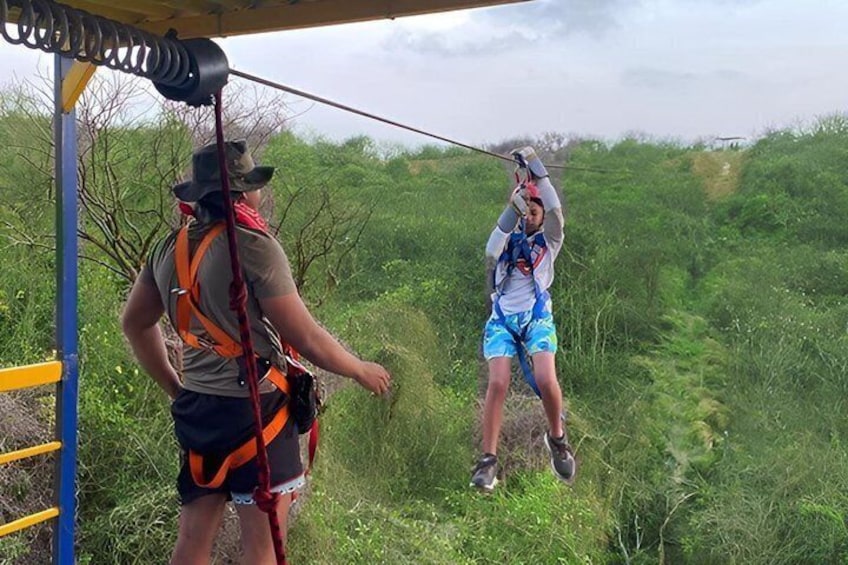 To personer gør sig klar til zip-lining med sikkerhedsudstyr og en zipline-konstruktion. 4