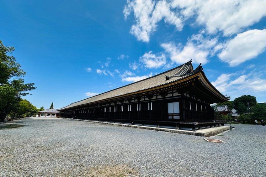 Un edificio japonés tradicional con tejado de tejas y estructura de madera, rodeado de grava y árboles. 4