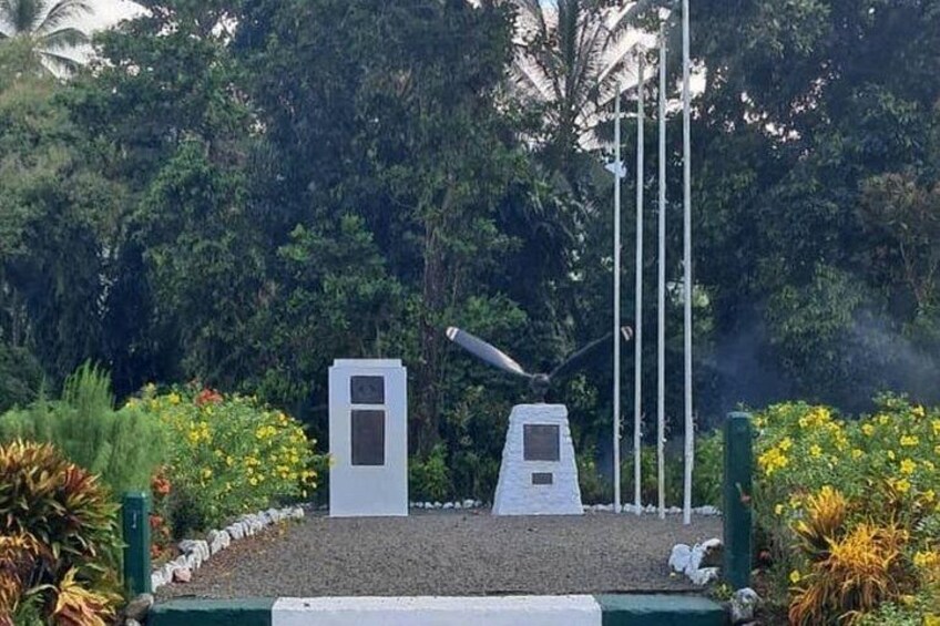 Un monumento con dos obeliscos blancos, rodeado de follaje y flores. 4
