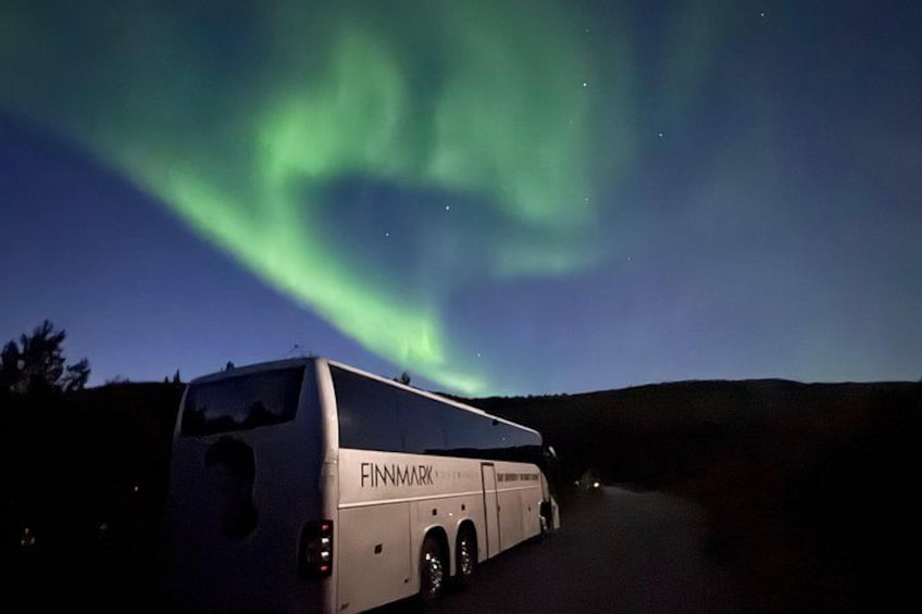 A bus with 'FINNMARK' written on the side parked on a road. 2