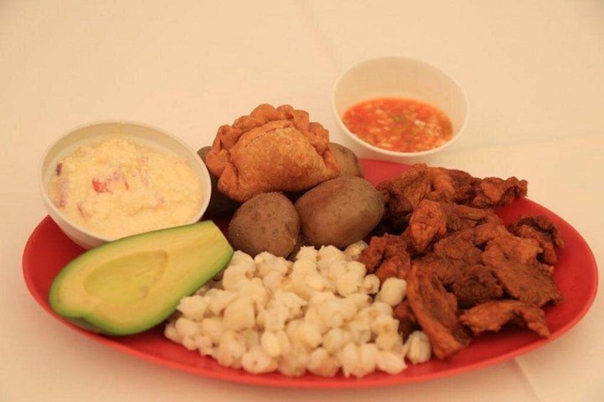 A plate with various food items including avocado, corn, fried chicken, and a side of salsa. 2