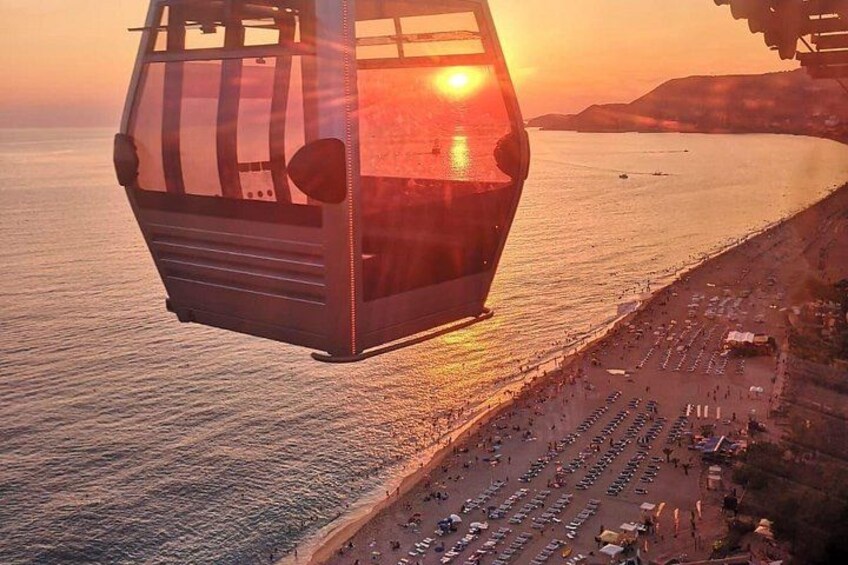 A cable car moving over a coastal area during sunset. 2
