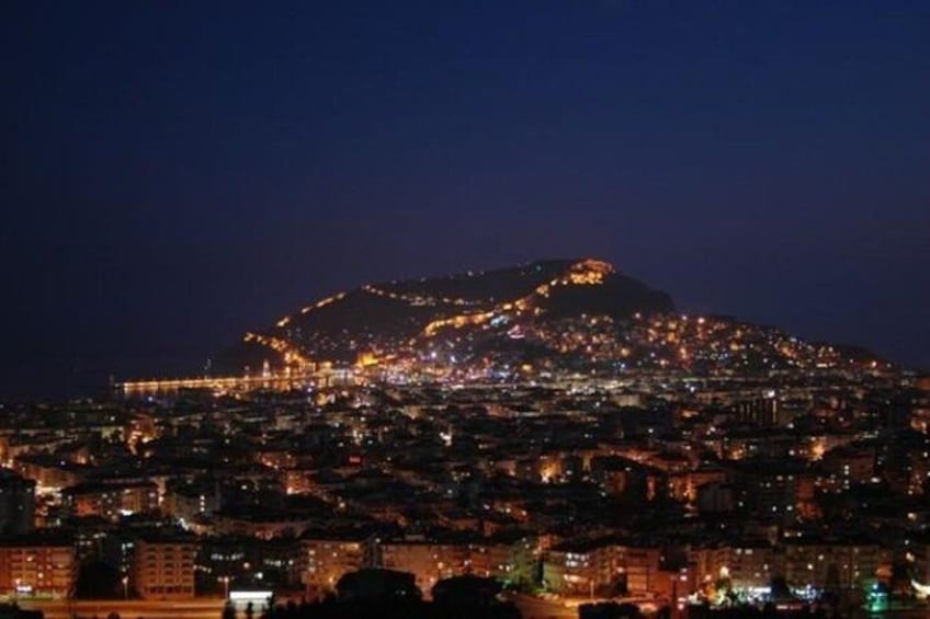A cityscape at night with a prominent hilltop illuminated by lights. 5