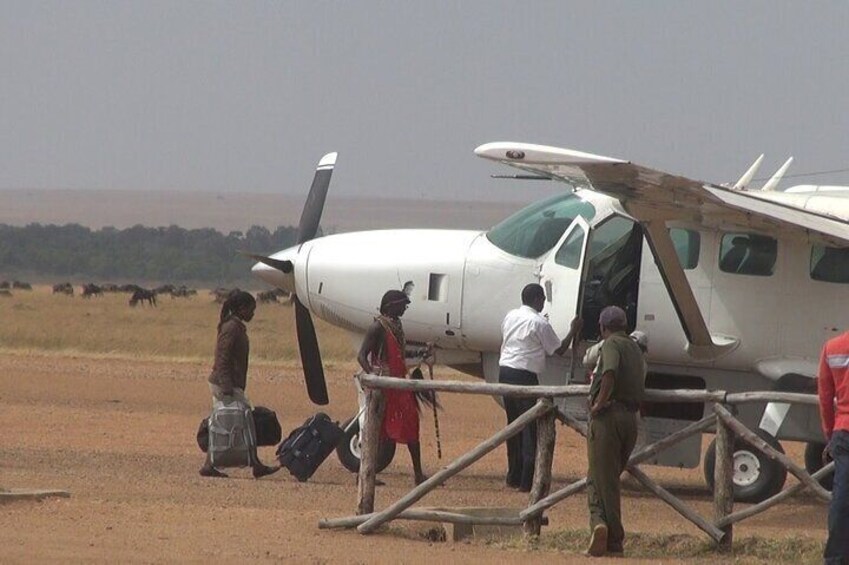 A small white aircraft with people boarding and disembarking. 5