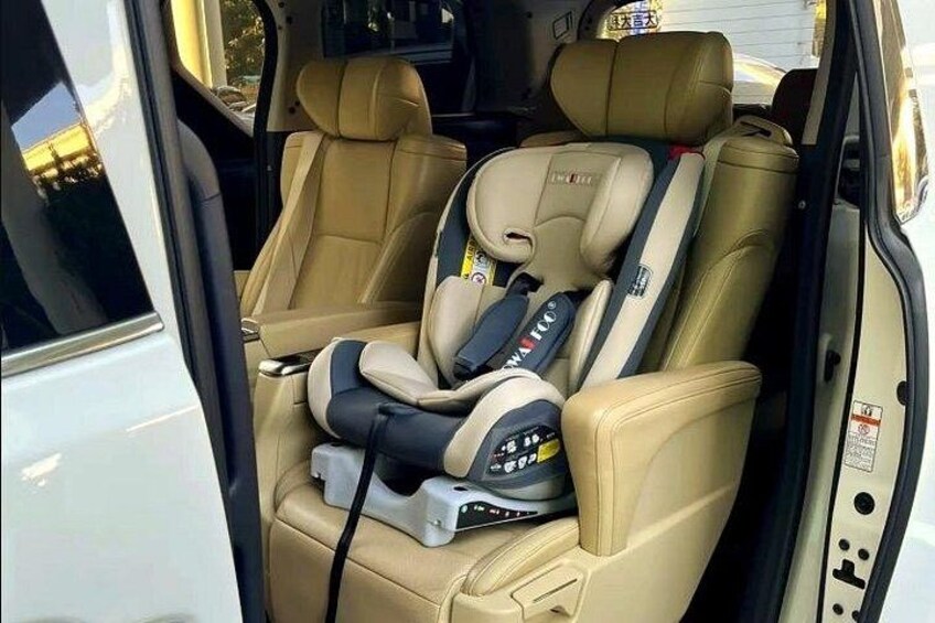 A vehicle interior with beige leather seats, a child car seat, and a control panel. 2