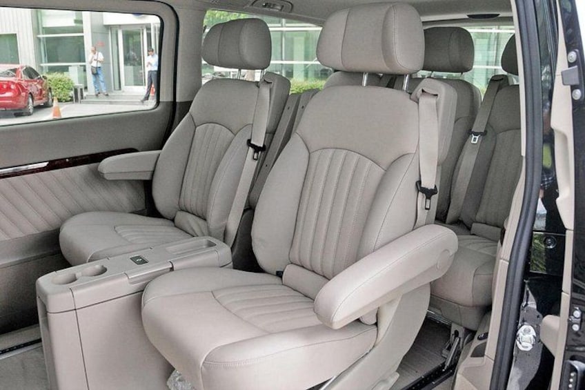 A vehicle interior with two beige leather seats, a center console, and a rearview mirror. 4