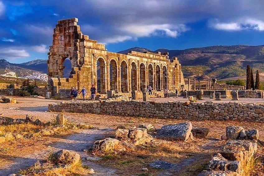 Ancient ruins with arches and columns, set against a mountainous backdrop. 2