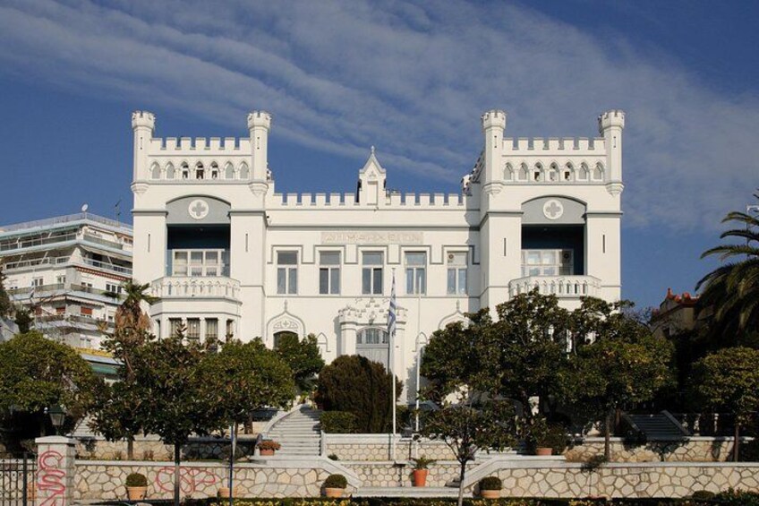 A castle-like building with a symmetrical facade, a central entrance, and a stone staircase leading up to it. 5