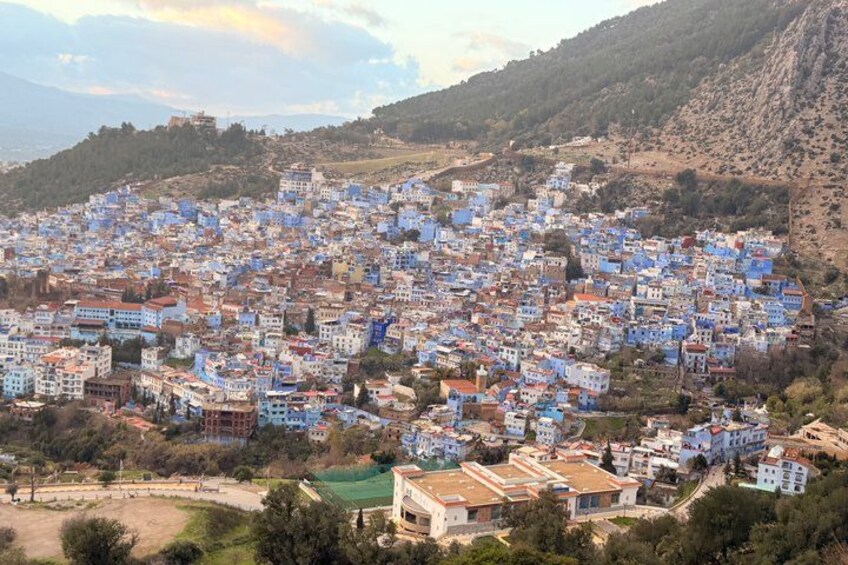 A densely packed town with buildings in blue and white, surrounded by hills. 4