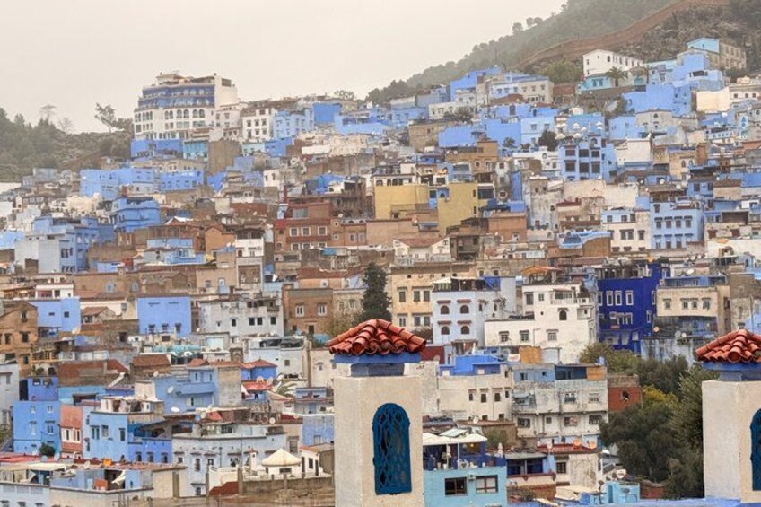 A densely packed cityscape with buildings painted in various shades of blue and white, with some featuring distinctive red-tiled roofs. 2