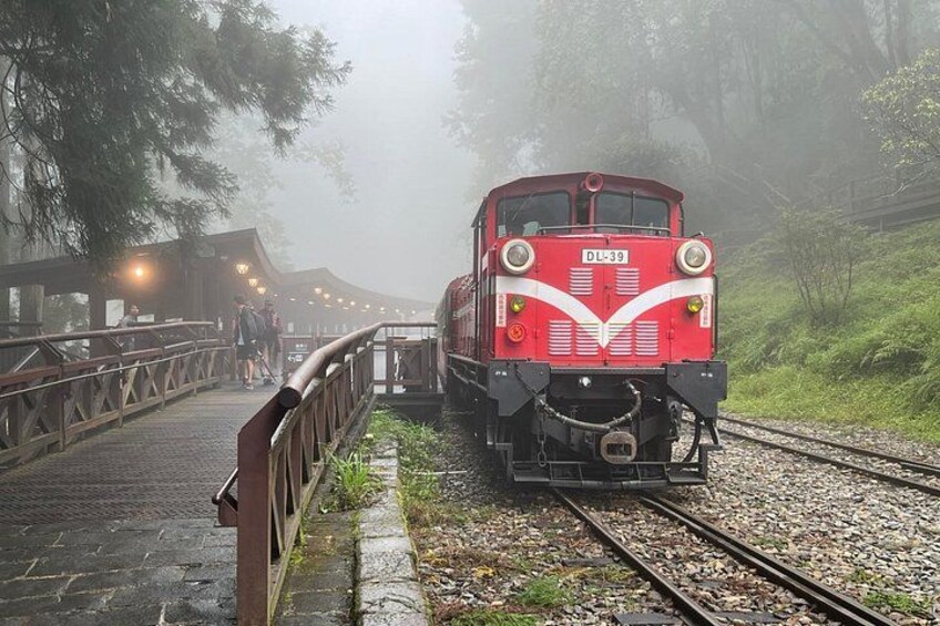 A red train on tracks with a wooden bridge in the background. 2