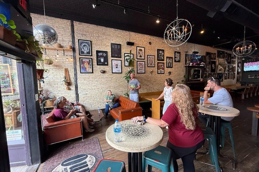 L’intérieur d’un café, avec des murs en briques, des œuvres d’art encadrées et des tables rondes. 1