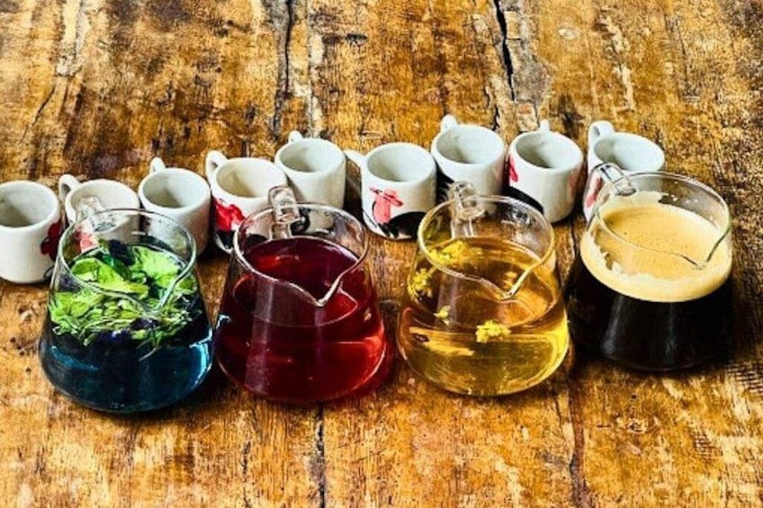 A wooden table with various cups and glasses containing different colored liquids, some with straws. 4