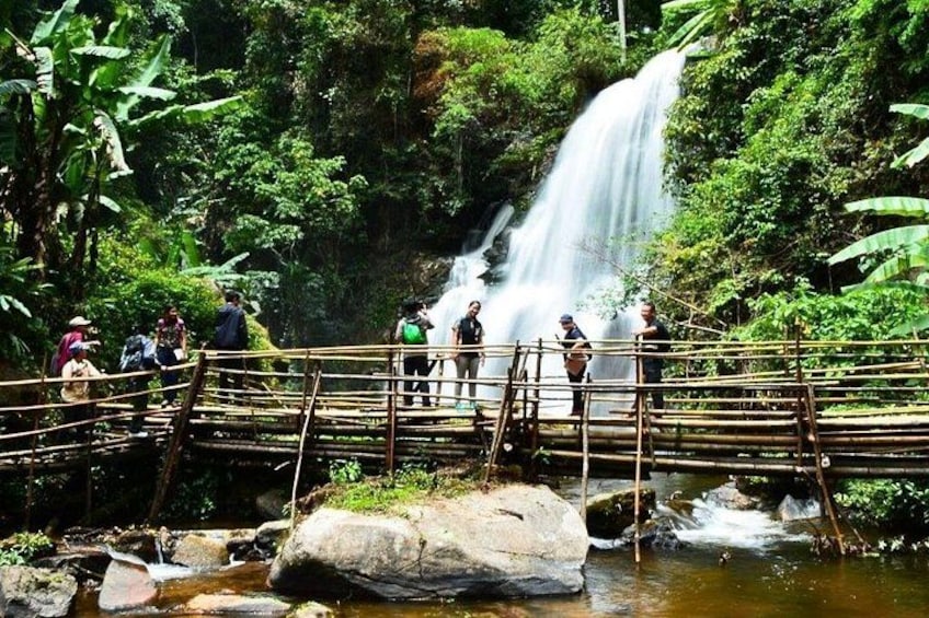 A waterfall, a wooden bridge, and people observing the scenery. 1