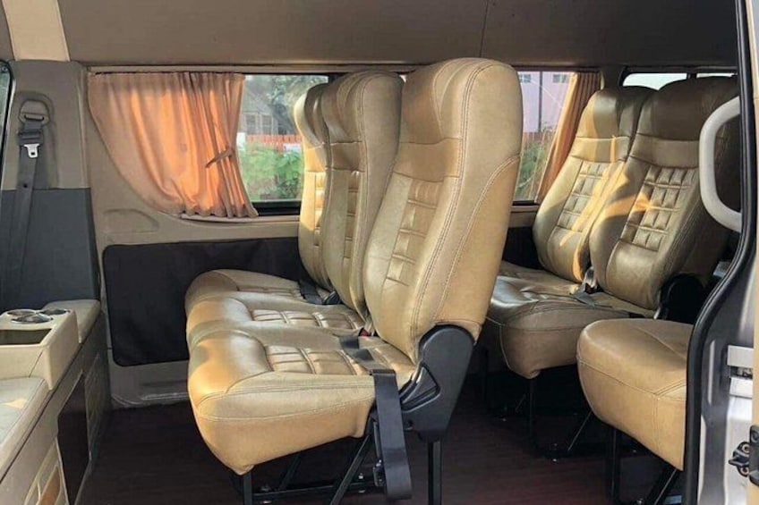 A vehicle interior with beige leather seats, a center console, and a window with curtains. 3