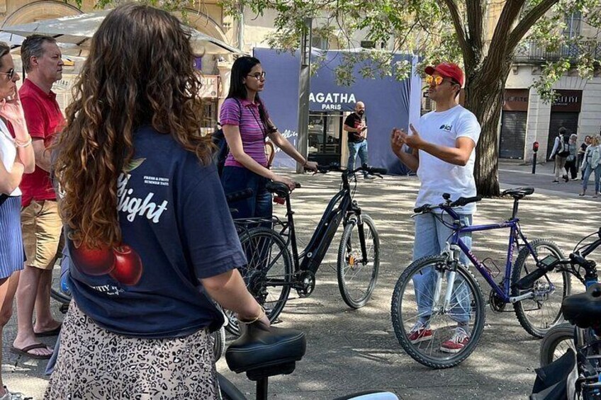 A group of people outdoors, some with bicycles, near a building with 'AGATHA PARIS' signage. 4