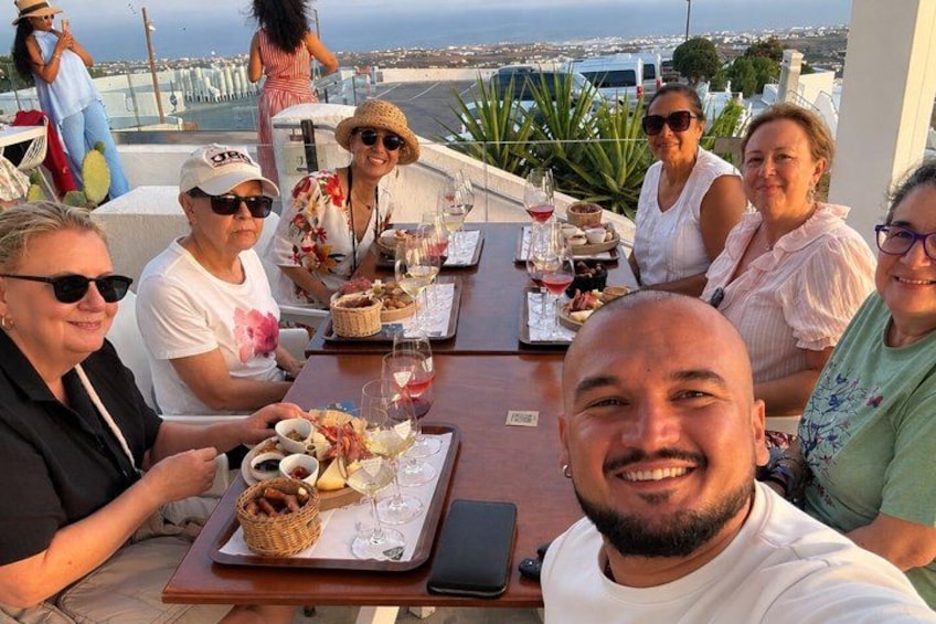 Eine Gruppe von Menschen speist an einem Tisch im Freien mit Blick auf das Meer. 4