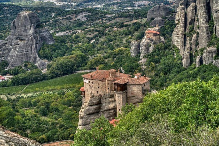 A monastery perched on a rocky cliff, surrounded by lush greenery and dramatic rock formations. 2