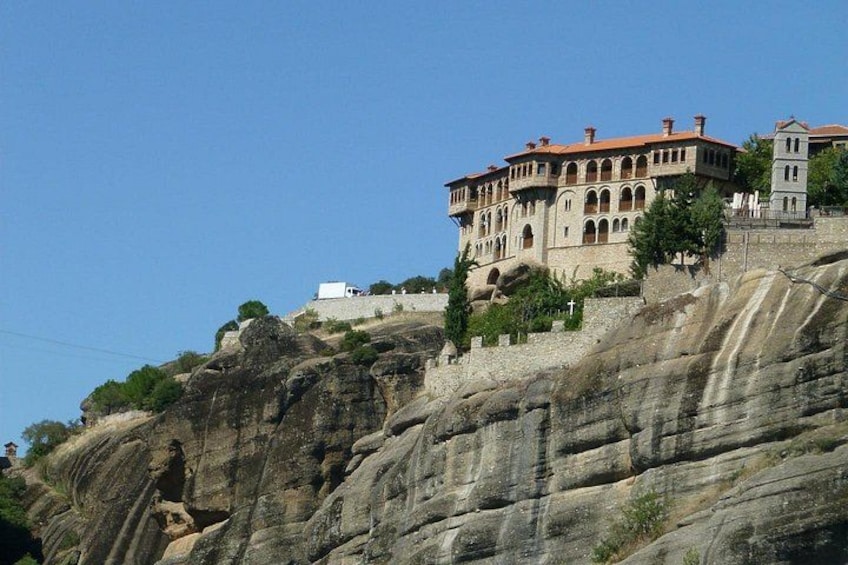 A building on a rocky hillside with a red roof and arched windows. 1