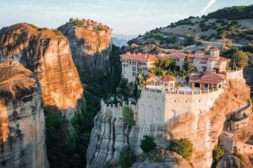 A monastery perched on a cliff, surrounded by rocky terrain and lush greenery. 5