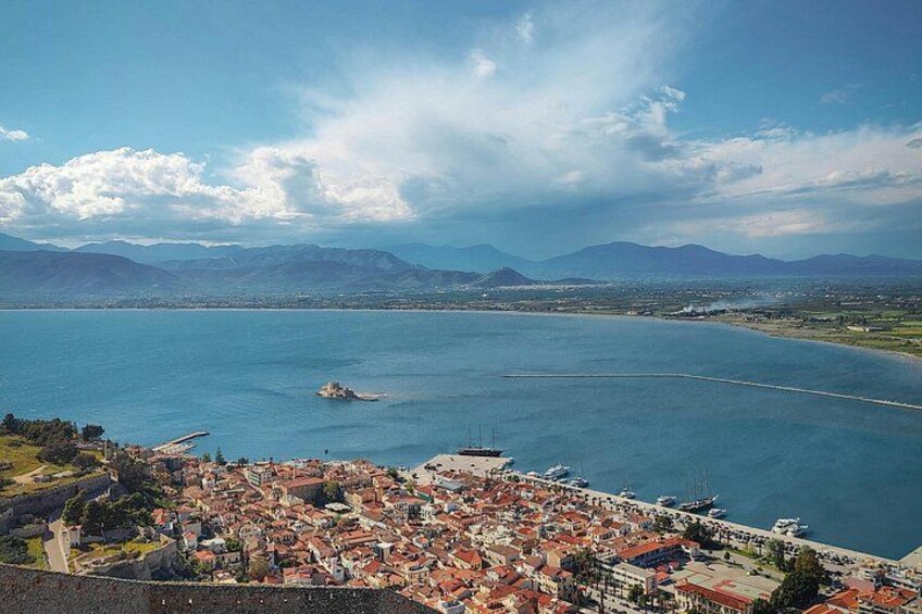 A coastal city with a large body of water, a prominent island, and a mountainous backdrop. 5