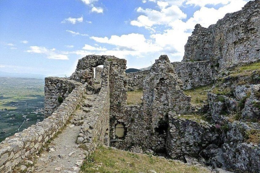 Ancient stone ruins with a pathway leading through them, overlooking a valley. 2