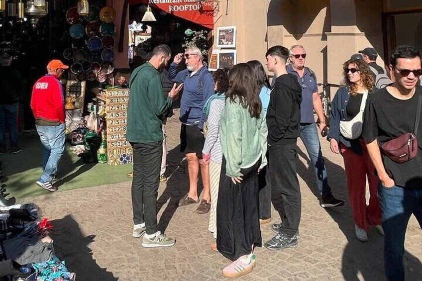 People standing and conversing in a market area with various stalls and a sign for 'Restaurant Rooftop'. 4