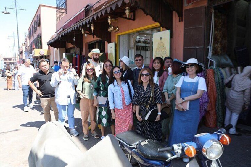A group of people standing in front of a building with a motorcycle parked nearby. 1