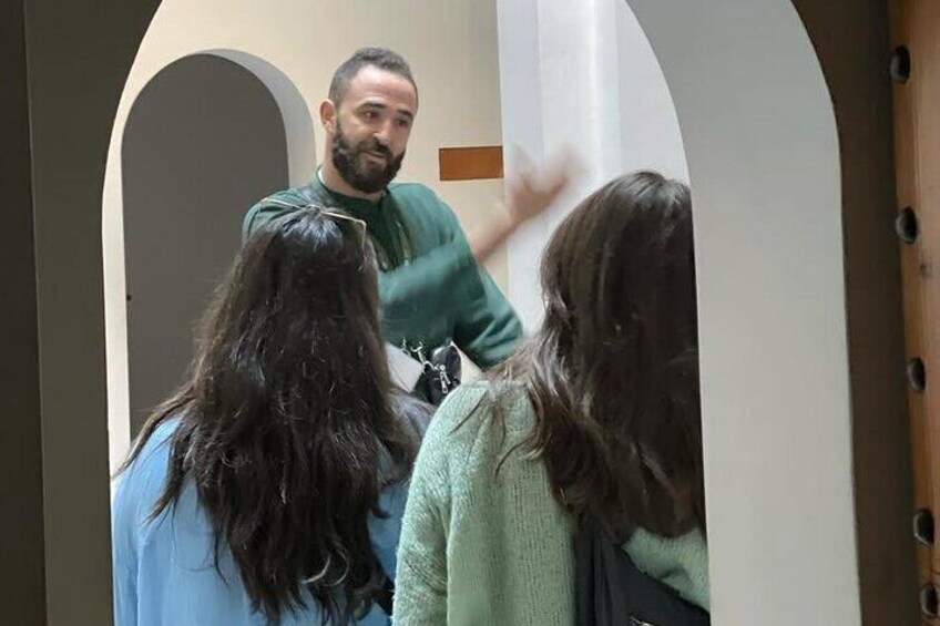 A person standing in a doorway with two people facing them. 2